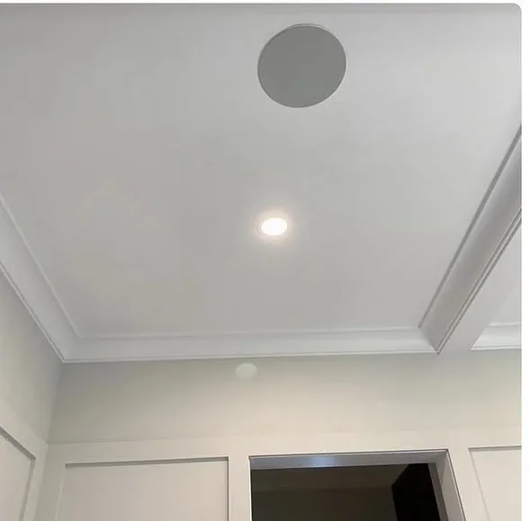 After drywall repair, showing a smooth finished ceiling with recessed light, speaker, and crown molding