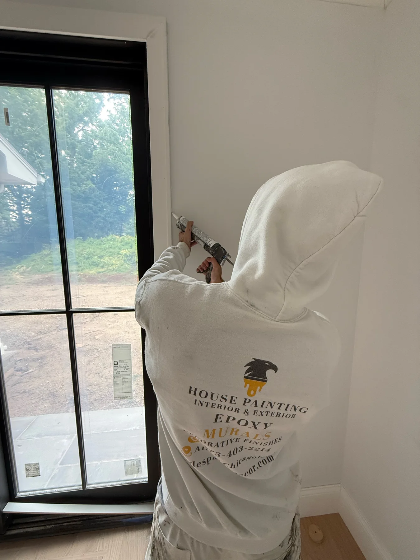 Eagles painter sealing trim at a black framed window during interior preparation