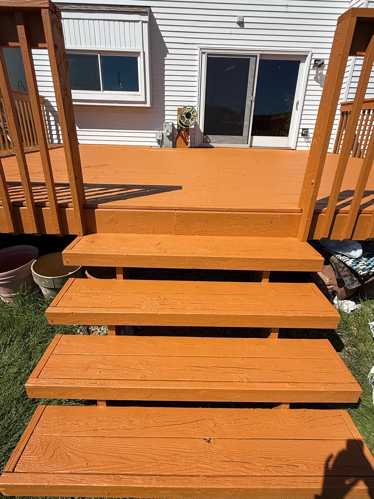 Finished wood deck, stairs, and railings beside a light sided residential exterior