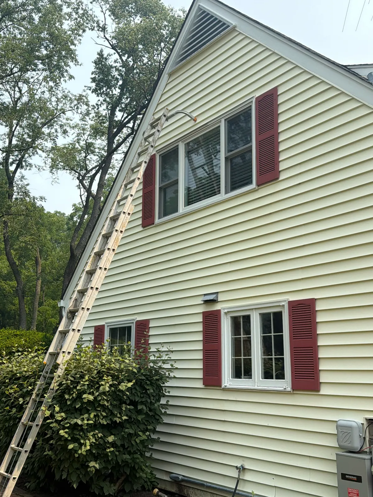 Extension ladder positioned against a light sided two-story residential exterior