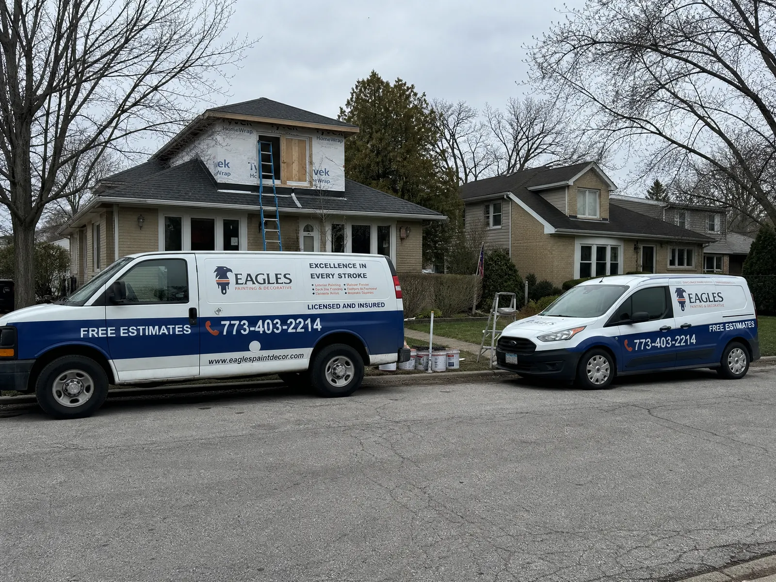 Exterior painting project mobilization with Eagles work vehicles, access equipment, and a residential facade