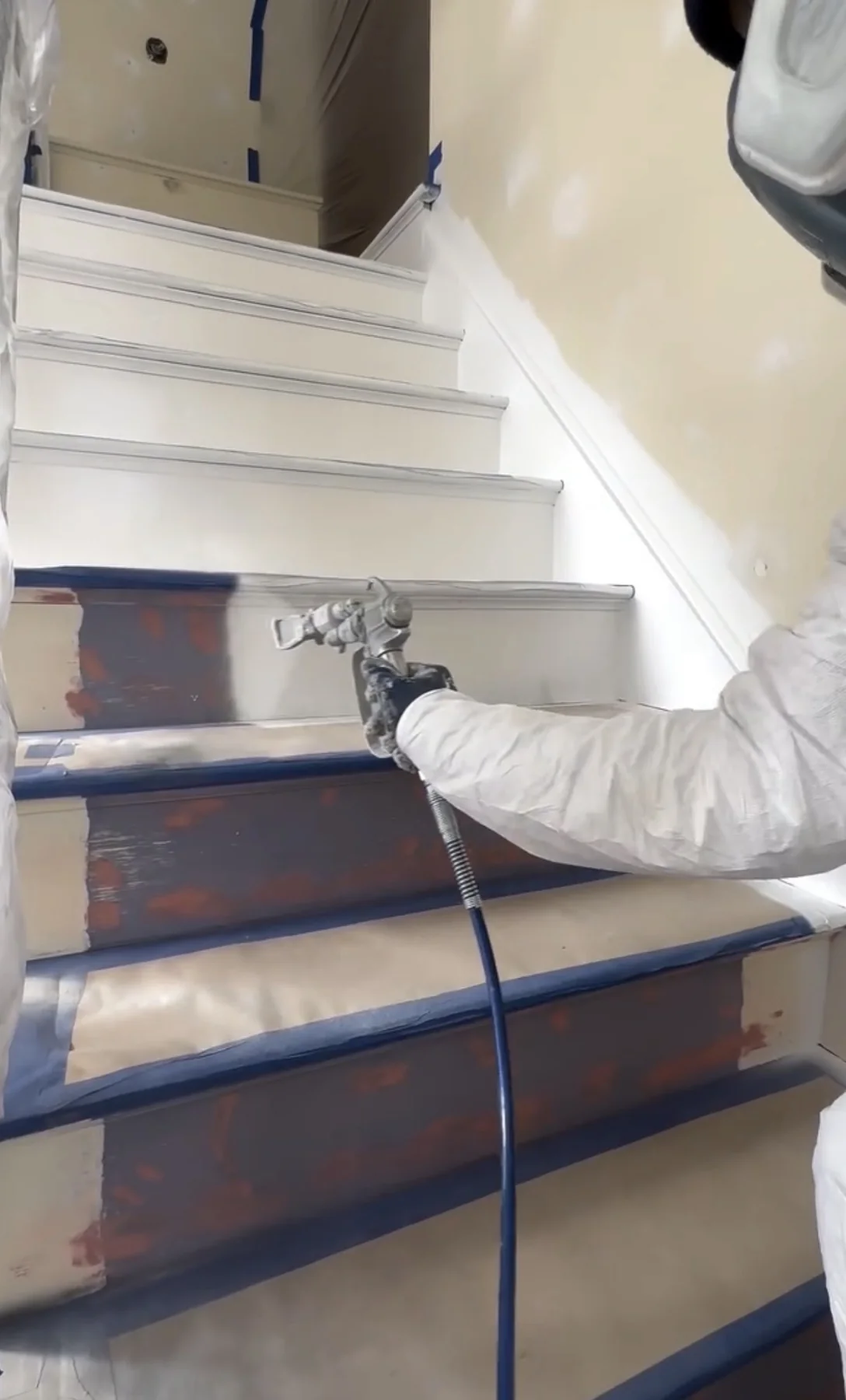 Painter applying a sprayed finish to a carefully masked interior staircase