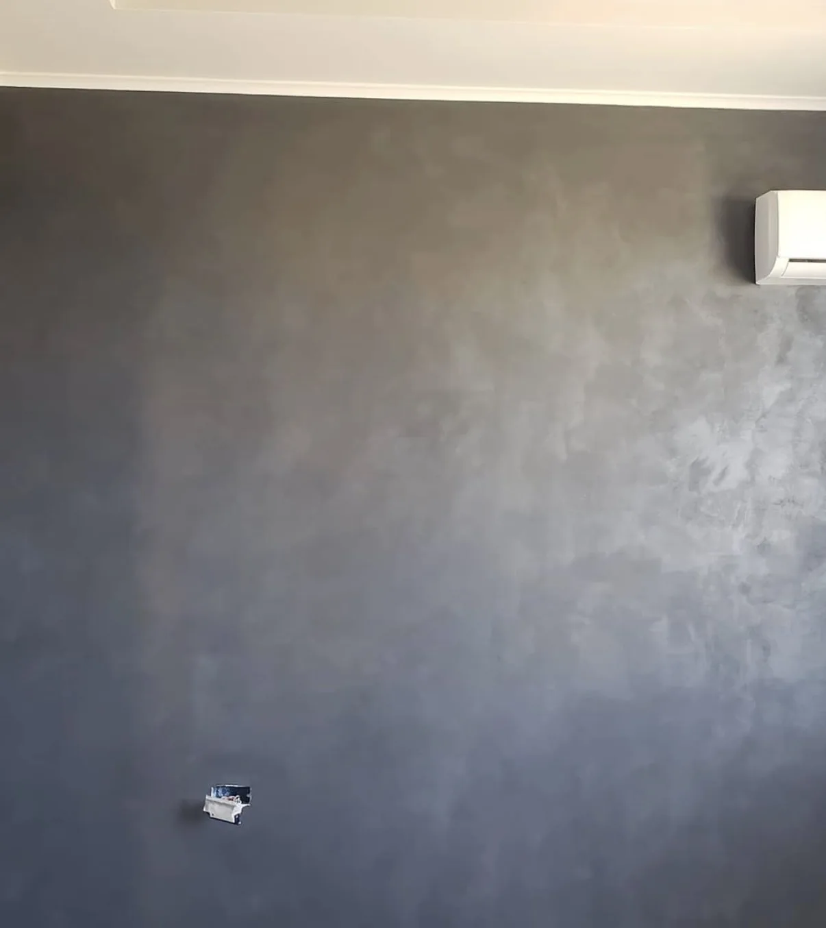 Gray-brown limewash wall with layered hand applied movement beneath white ceiling trim