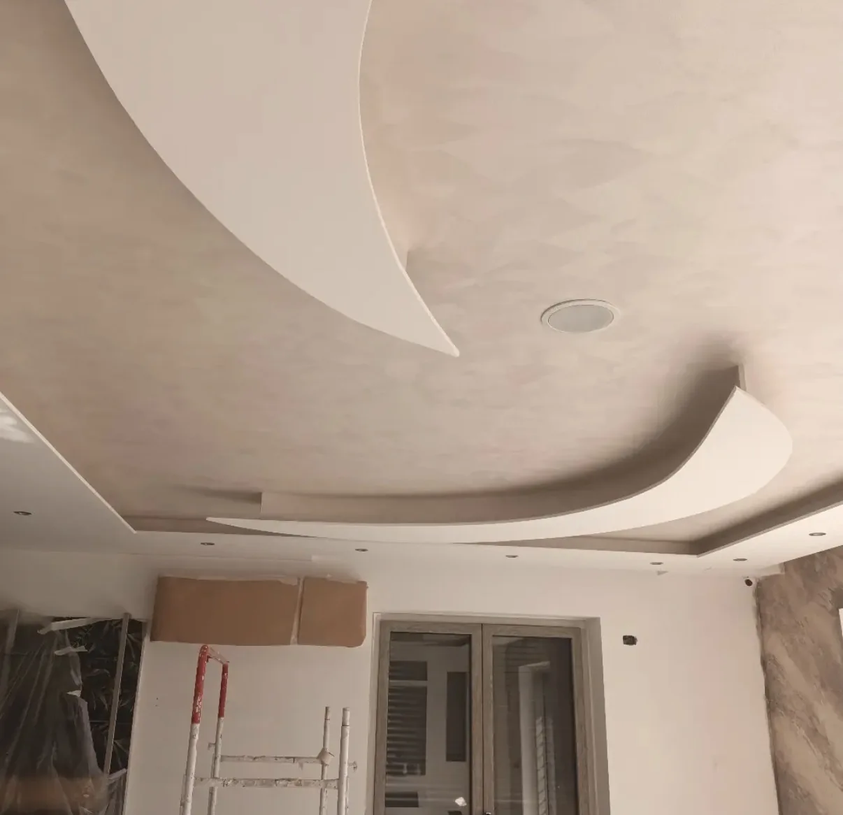 Warm beige limewash across a sculpted curved ceiling during an interior installation