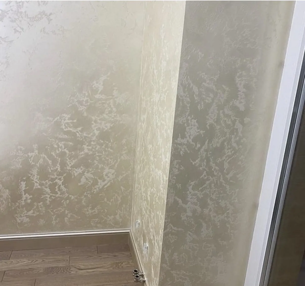 Pale warm Venetian plaster continuing across two adjoining interior wall planes