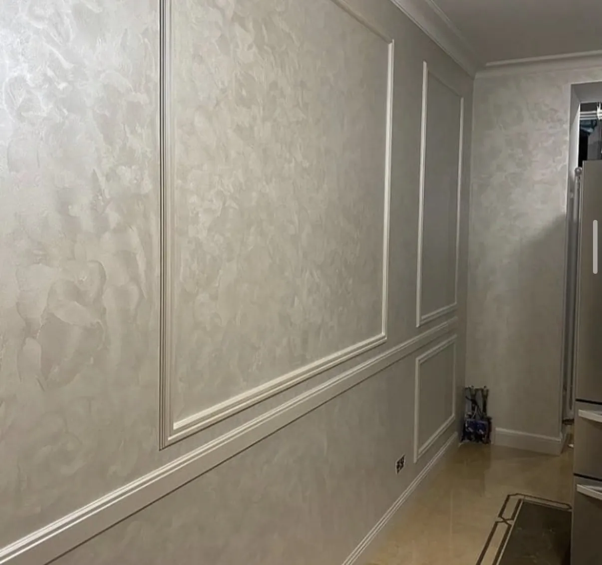 Venetian plaster applied across paneled corridor walls with soft warm gray movement