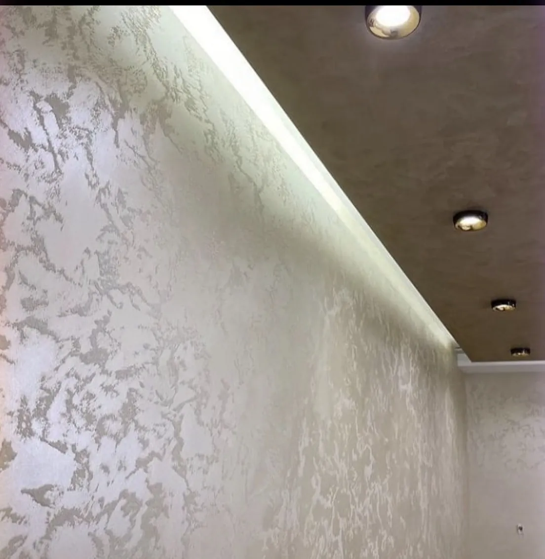 Angled view of light gray green Venetian plaster beside a wood toned ceiling