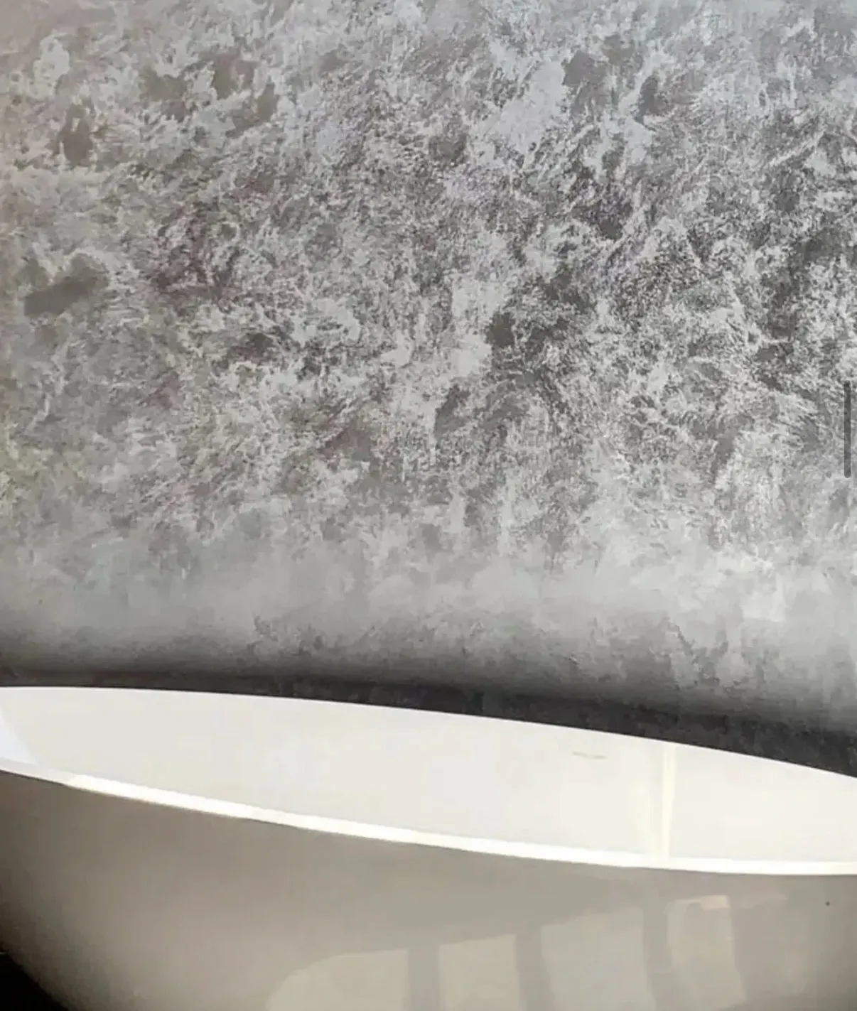Close study of pale gray and off white Venetian plaster above a smooth curved surface
