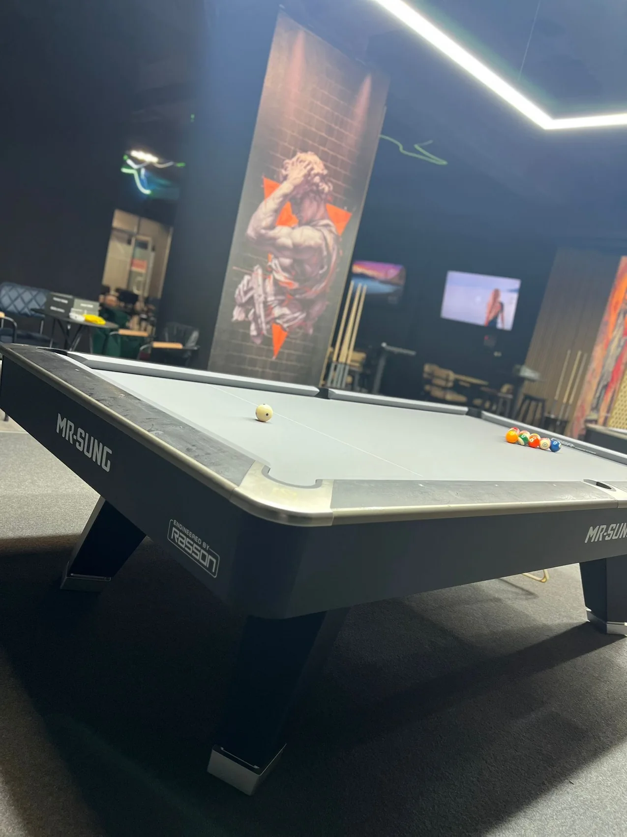 Dark mural of a stylized boxer with orange accents installed behind a pool table in an entertainment room